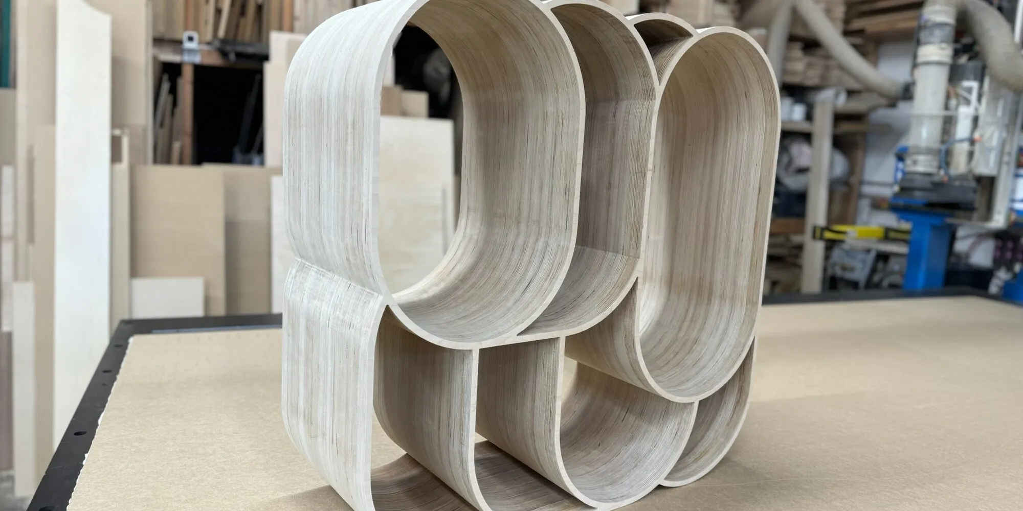A laminated plywood form with curved openings, CNC-routed and sitting on the router bed